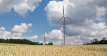 Two wind power stations behind a wheat field.