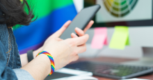 Woman sending a text on cell phone with rainbow bracelet on wrist. 