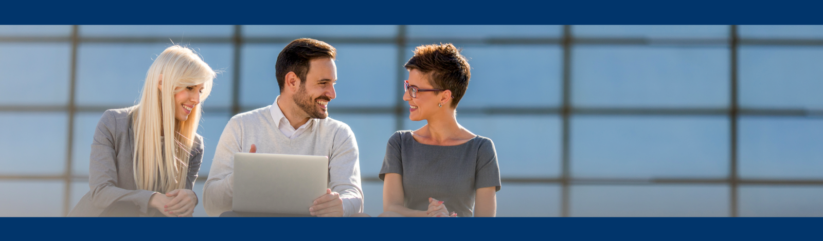 Three business people outdoors looking at a computer